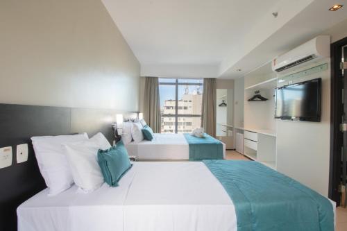 um quarto de hotel com duas camas e uma televisão de ecrã plano em Acqua Prime Maceió Ponta Verde em Maceió