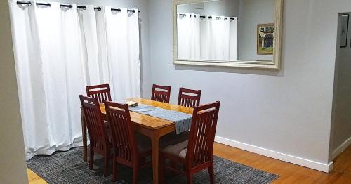 a dining room table with chairs and a mirror at Rose Holiday Home in Durban