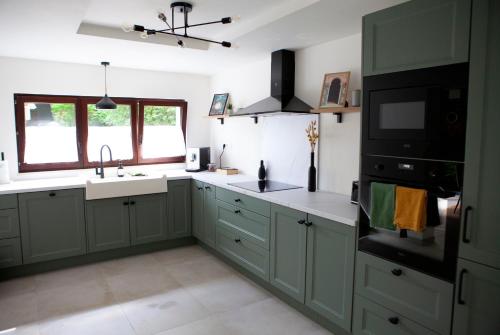 a kitchen with green cabinets and a sink at Oboho - Le gîte bohème (Pieds dans l’eau - Lit King Size - Jardin) in Esneux