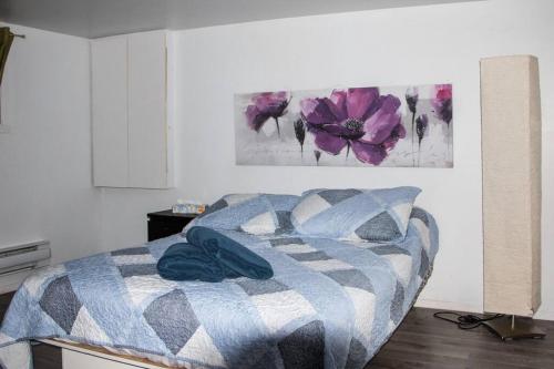 1 dormitorio con 1 cama con una pintura floral en la pared en Maison rose du bord de mer à 5 min de st Luce en Sainte-Luce-sur-Mer