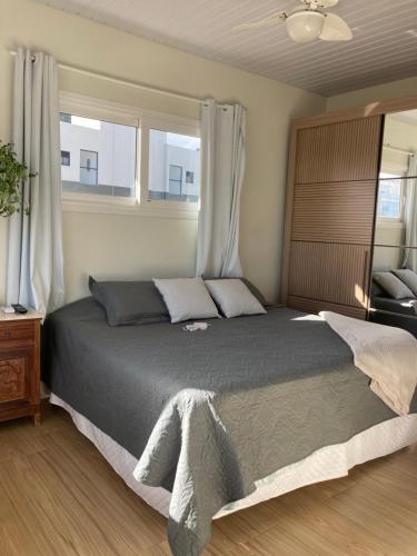 1 dormitorio con 1 cama grande y 2 ventanas en Apartamentob301 coliving bombinhas, en Bombinhas