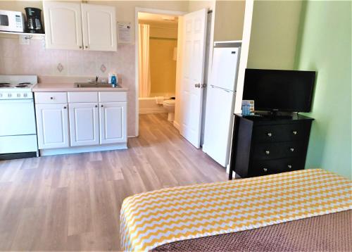 a kitchen with white cabinets and a television in a room at Johns Pass Beach Motel in St Pete Beach