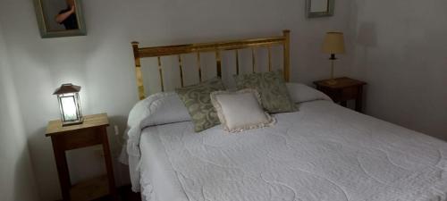 una camera da letto con un letto bianco e cuscini sopra di Los Cedros a Córdoba