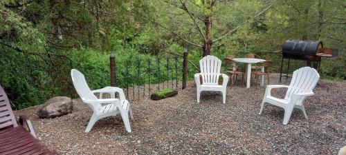 eine Gruppe von weißen Stühlen, einem Tisch und einem Grill in der Unterkunft Los Cedros in Cordoba