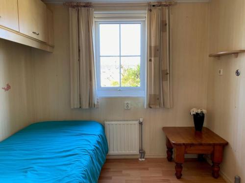 een slaapkamer met een bed, een tafel en een raam bij chalet Klein Vechtdal in Ommen