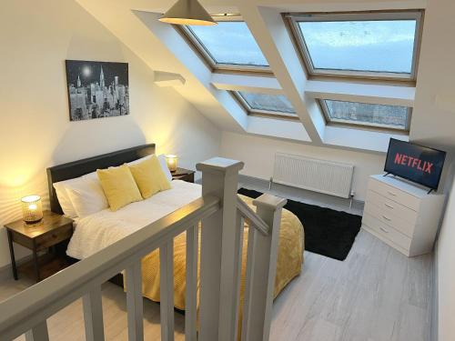 um quarto no sótão com uma cama e uma televisão em New Two Bedroom Premium Apartment - Skylight - Northampton Town Centre em Northampton