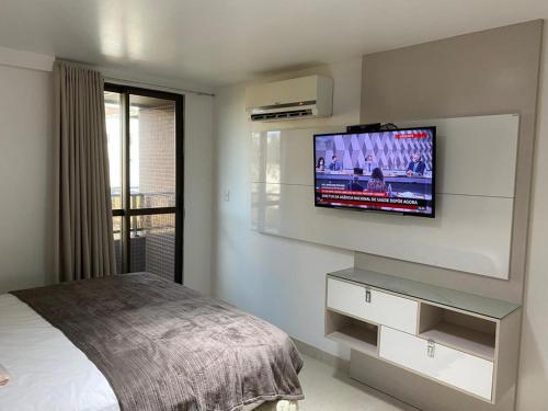 Un dormitorio con una cama y un televisor de pantalla plana en la pared. en Paraíso do Atlântico Club Residence, en Cabedelo