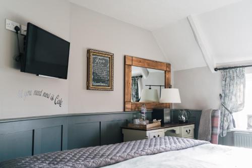 a bedroom with a bed and a tv on the wall at The Crown Inn in Gayton