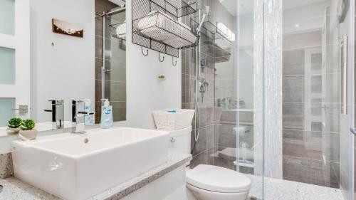 a white bathroom with a toilet and a shower at City Side Near Cook Street Village in Victoria