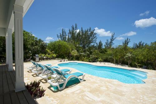 a group of lounge chairs and a swimming pool at Aqua Villa home in Governorʼs Harbour