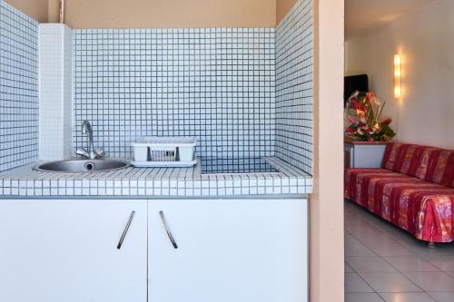 a kitchen with a sink and a red couch at Diamant Beach in Le Diamant