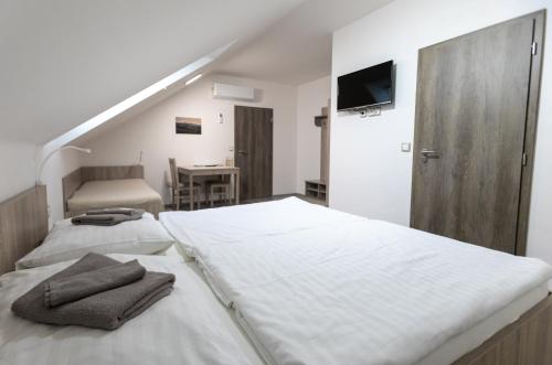 ein weißes Schlafzimmer mit 2 Betten und einem TV in der Unterkunft Apartmány Za Dvorem in Velké Pavlovice