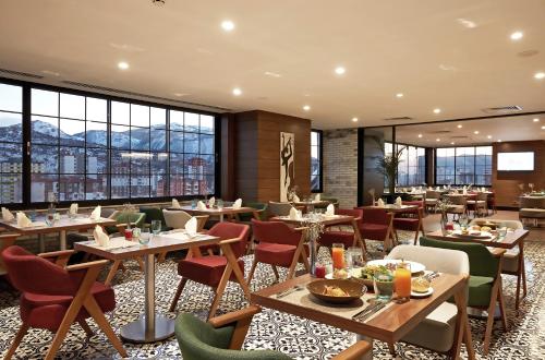 a restaurant with tables and chairs and windows at Dedeman Kayseri in Kayseri