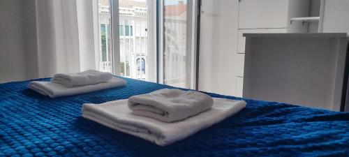 2 toallas en una cama azul con ventana en Bungalow Deluxe Gran Alacant en Gran Alacant