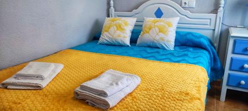 a bedroom with a yellow bed with towels and pillows at Bungalow Deluxe Gran Alacant in Gran Alacant