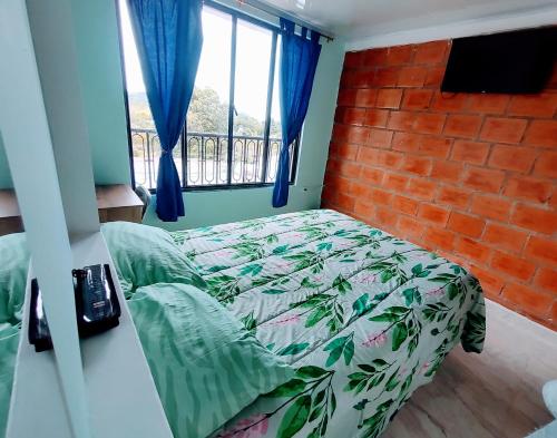 a bedroom with a bed and a brick wall at ApartaHotel El Balcón del Tolima in Falan