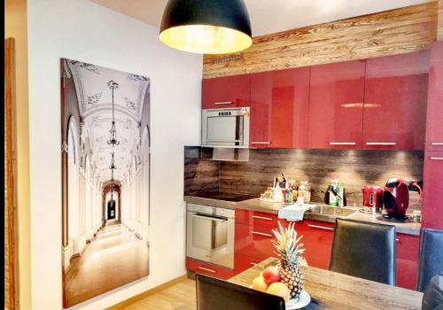 克萊恩 蒙塔納的住宿－Apartment 32 Crans-Montana，厨房配有红色橱柜和 ⁇ 萝桌