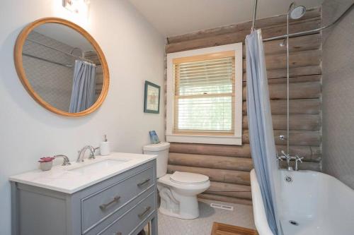 La salle de bains est pourvue d'un lavabo, de toilettes et d'un miroir. dans l'établissement Cabin and Creek - Secluded Oasis - 3BD, à Kingston Springs