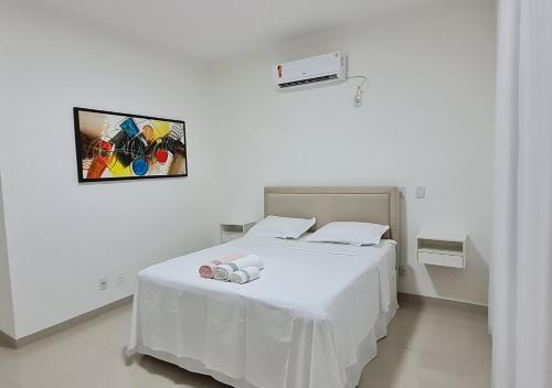 a white bed in a white room with a picture on the wall at Apartamento no centro próximo a JK. in Palmas