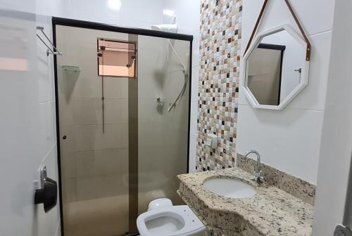 uma casa de banho com um chuveiro, um lavatório e um WC. em Apartamento no centro próximo a JK. em Palmas