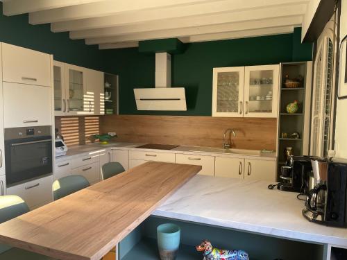 - une cuisine avec une table en bois et des murs verts dans l'établissement A l'orée d'Arras, à Saint-Laurent-Blangy