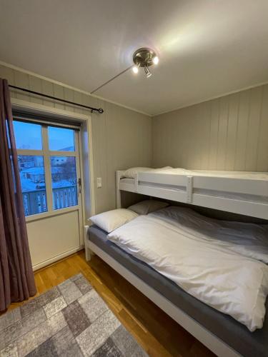 two beds in a room with a window at Stetind - Modern apartment with free parking in Narvik