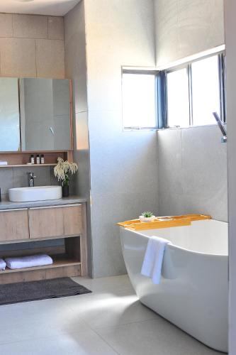 a bathroom with a tub and a sink and a mirror at Square Connexions Guest House in Gaborone
