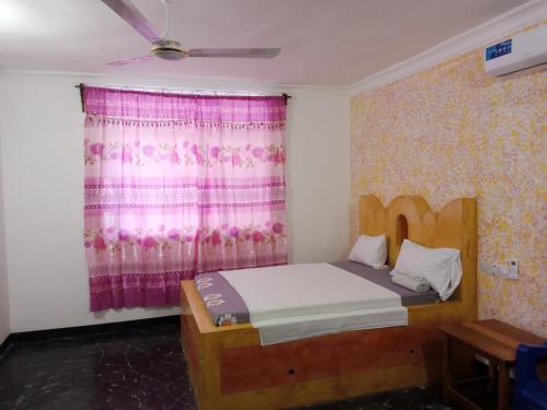 a bedroom with a bed and a window with a pink curtain at Ndiro Beach House Kendwa in Kendwa