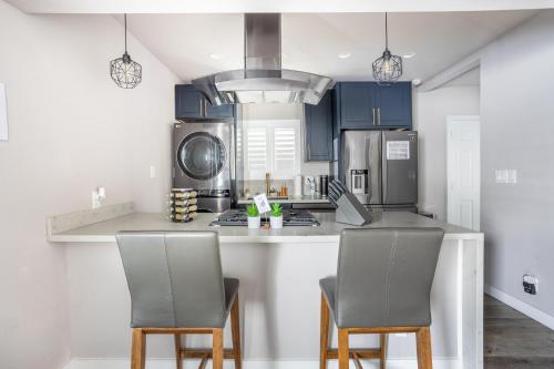 a kitchen with blue cabinets and a counter with two chairs at Fam Friendly 2BD 8min from airport, 4min from SoFi in Los Angeles