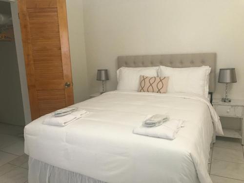 1 dormitorio con 1 cama blanca grande y toallas. en Compassionate Touch Spa en Newcastle Village