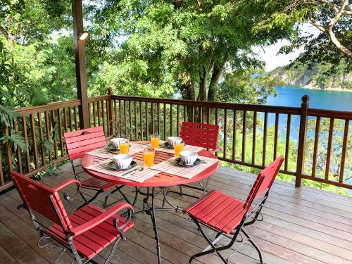 a table and chairs on a deck with a view of the water at Villa Palm Bay Stunning View 5 min to beach 3 min to downtown King size bed in Deshaies