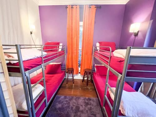 a room with three bunk beds with red sheets at ITH San Diego Adventure Hostel in San Diego