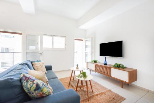 uma sala de estar com um sofá azul e uma televisão de ecrã plano em Lily of the Valley by HolyGuest em Tel Aviv