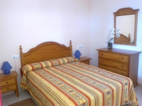 sypialnia z łóżkiem, komodą i lustrem w obiekcie Apartamento Amatista Calpe w mieście Calpe