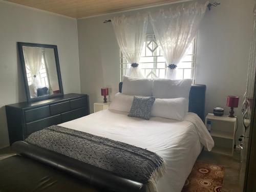 a bedroom with a large white bed with a window at Samkab Legacy & Comfort in Lusaka