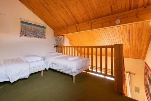 two beds in a room with a balcony at La Belette - Duplex au charme savoyard avec vue sur la montagne in Les Allues