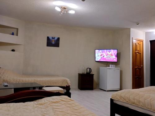 Habitación con 2 camas y TV en la pared. en Rest Home Hotel, en Nizhny Novgorod