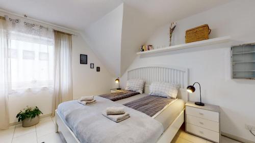 a white bedroom with two beds and a window at Apartmenthaus Celik in Bielefeld