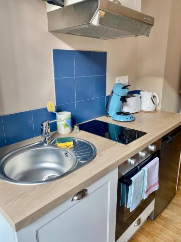 a kitchen with a sink and a blue tiled wall at Hostellerie Alsacienne de Masevaux in Masevaux