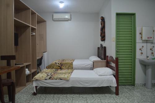 a room with two beds and a green door at Pousada Encantos da Amazônia in Alter do Chao