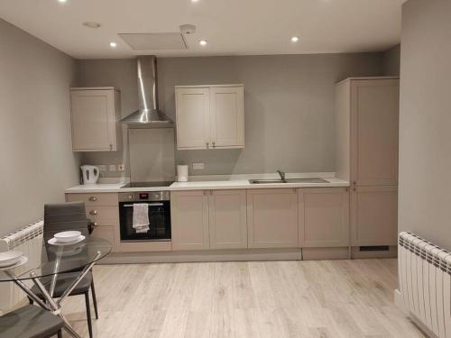 a kitchen with white cabinets and a stove top oven at Central Huddersfield Apartment in Huddersfield