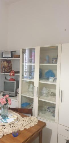 una cocina con una mesa y un armario lleno de platos en Casa vacanze Cagliari,, en Cagliari