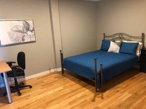 a bedroom with a bed with blue sheets and a desk at Condo 101 centre-ville de Rimouski près du fleuve in Rimouski