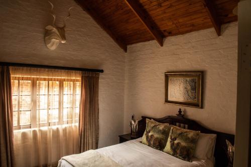 a bedroom with a bed and a window at Critchley Hackle - Managers Cottage in Dullstroom