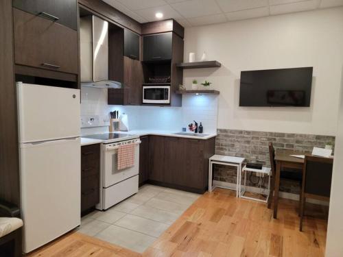 a kitchen with a white refrigerator and a table at Loft 102 au cœur de Rimouski près du St-Laurent in Rimouski