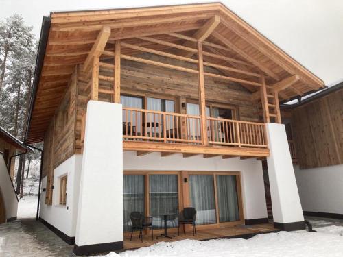 a log home with a deck on the side of it at Les Ciases Chalets Dolomites in San Vigilio Di Marebbe