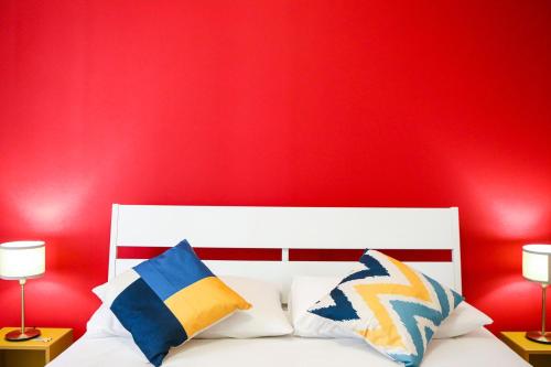 a bedroom with a red wall and a bed with pillows at Materdays 24 in Naples