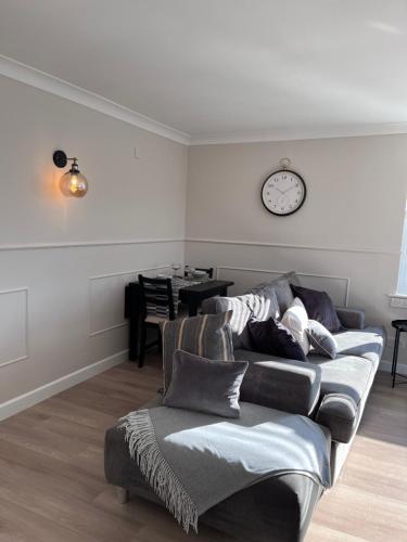 a living room with a couch and a clock on the wall at Two-bedroom Apartment in Yeovil