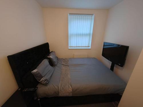 a small bedroom with a bed and a television at Modern Huddersfield apartment in Huddersfield