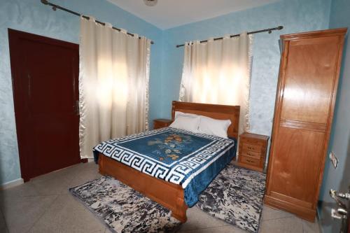 ein Schlafzimmer mit einem Bett mit einem Bettrahmen aus Holz und einer Tür in der Unterkunft حي الشهداء in El Aaiún